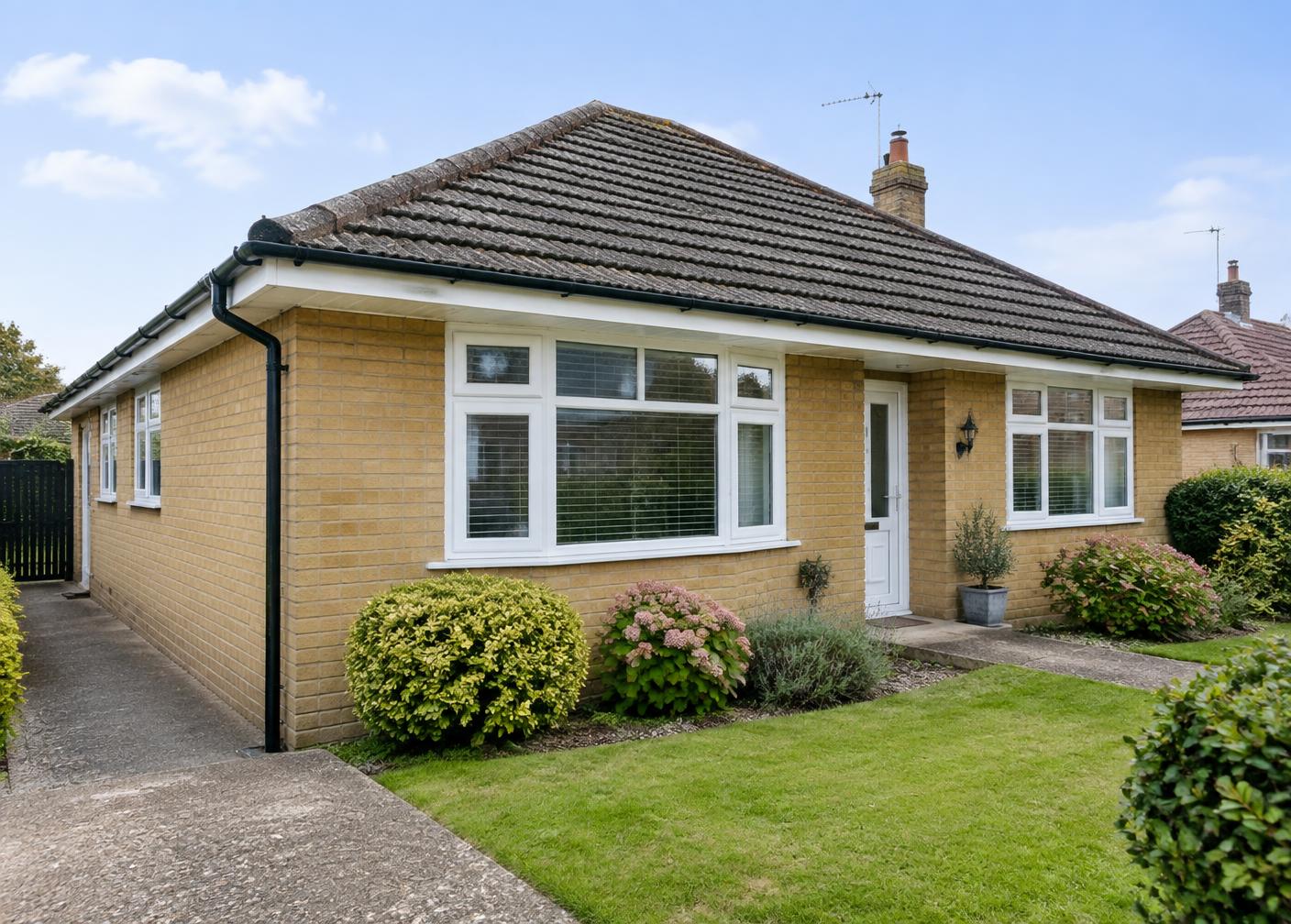 English yellow-brick bungalow with white fascias, soffits and black guttering